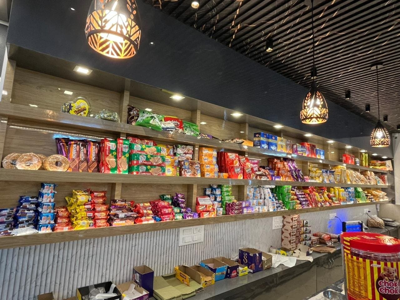 Bakery interior with wood-finish open display shelving, pendant lights and fluted counter base